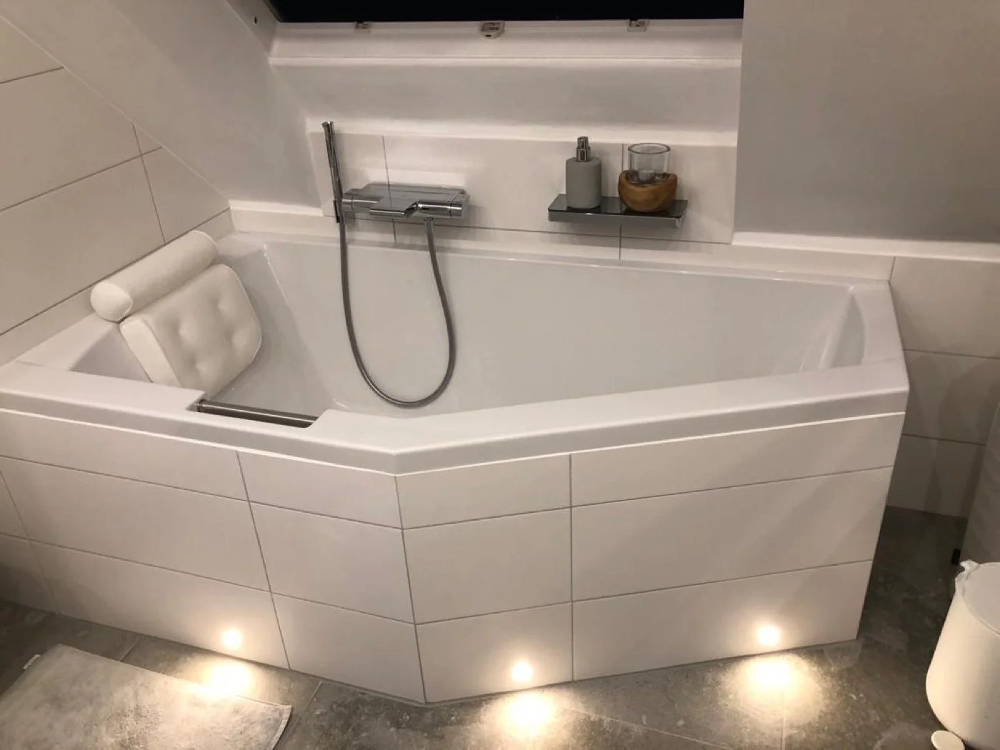 Elegante Badewanne mit weißen Fliesen, indirekter LED-Beleuchtung und eingebauter Nische