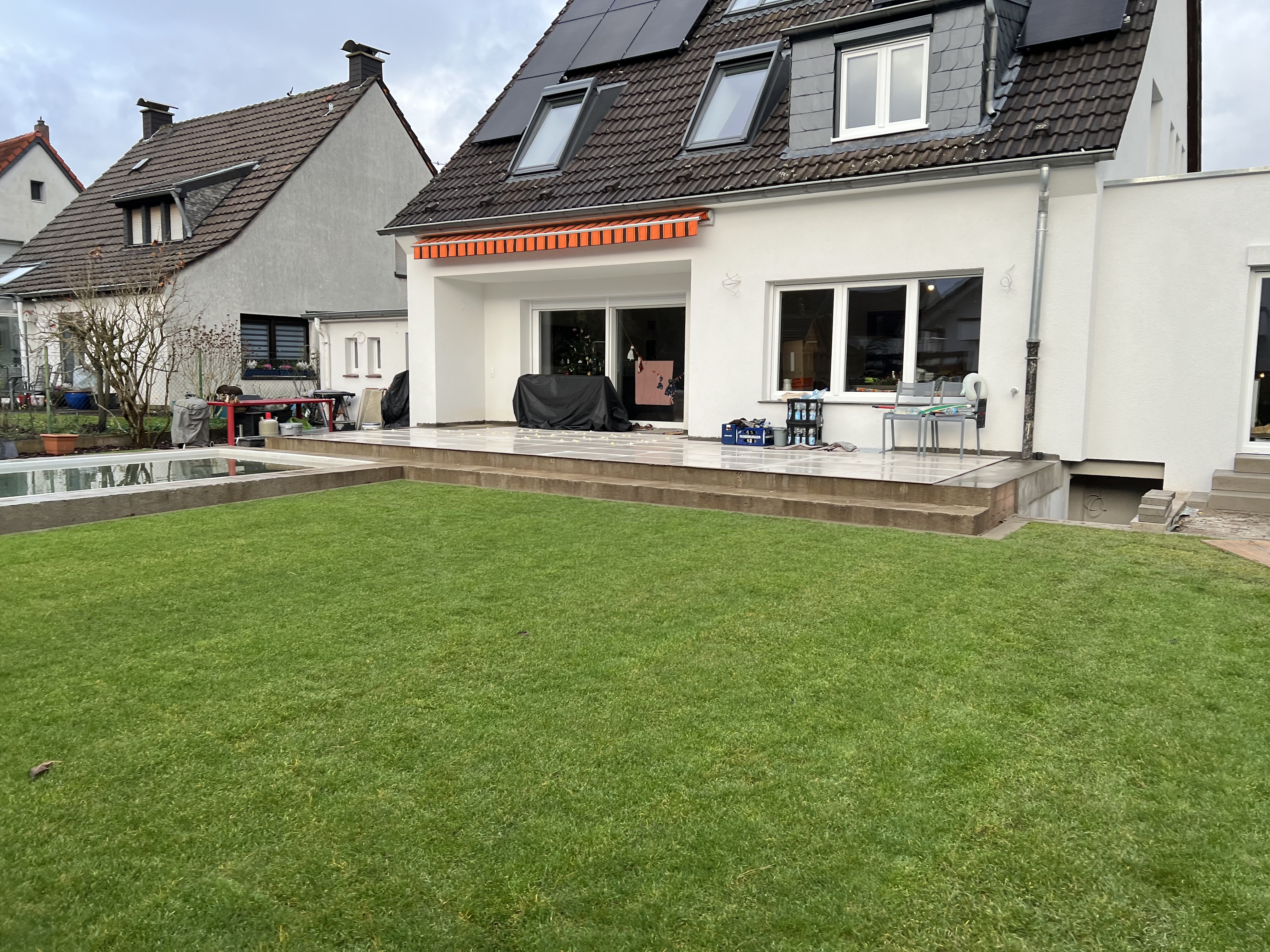 Einfamilienhaus mit mehrstufiger Natursteinterrasse, gepflegtem Rasen und Sonnenschutzmarkise