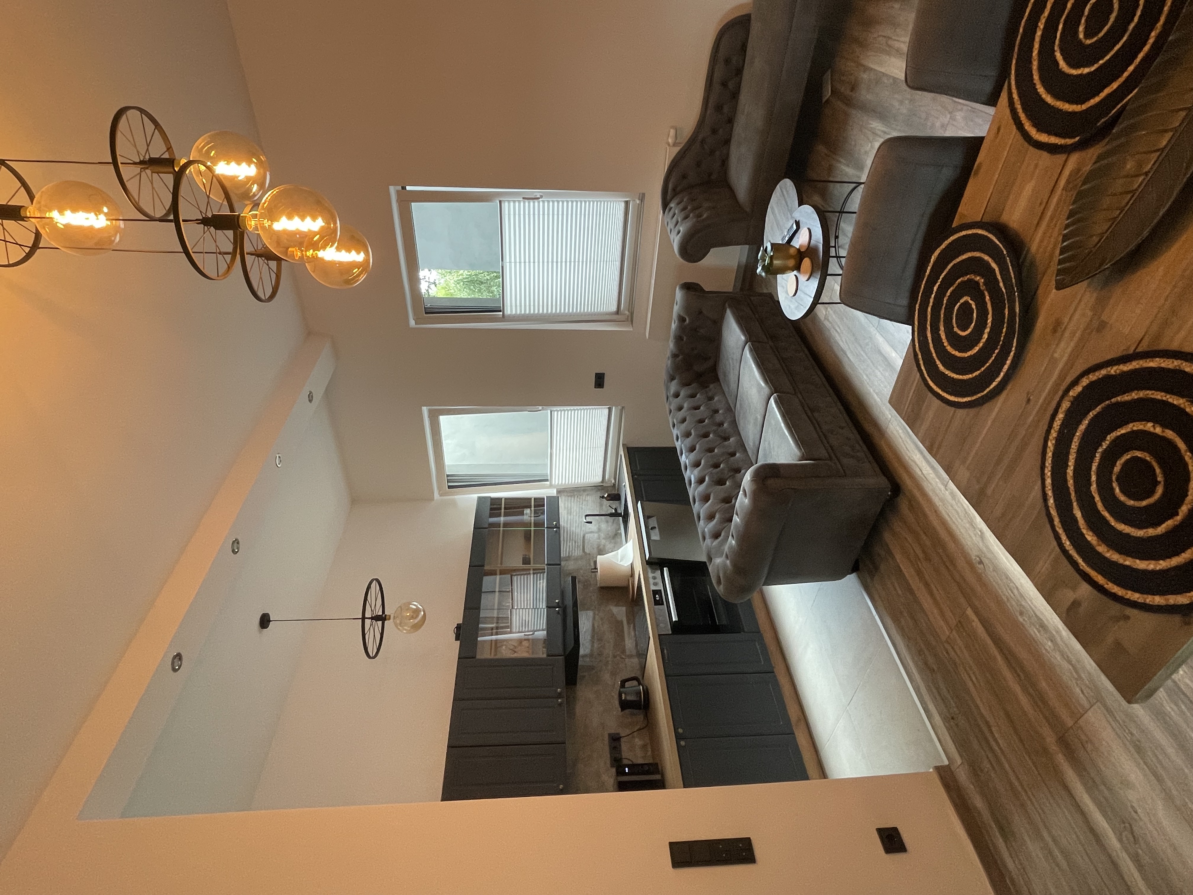 Wohnzimmer mit Chesterfield-Sofas, dekorativen Pendelleuchten und Holzwandverkleidung